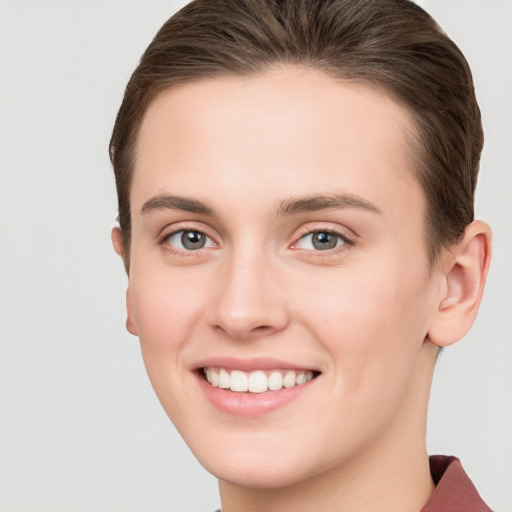 Joyful white young-adult female with short  brown hair and grey eyes