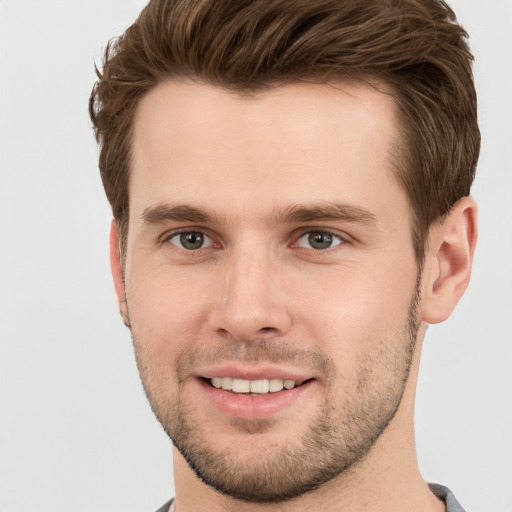 Joyful white young-adult male with short  brown hair and grey eyes