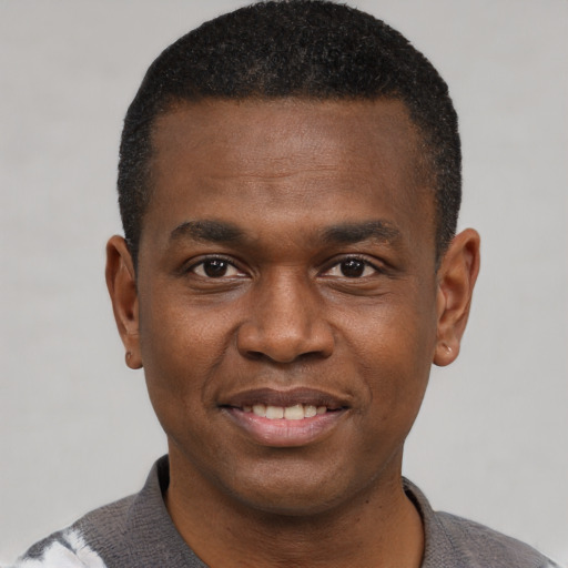 Joyful black young-adult male with short  black hair and brown eyes