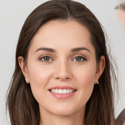 Joyful white young-adult female with long  brown hair and grey eyes