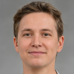 Joyful white young-adult male with short  brown hair and grey eyes