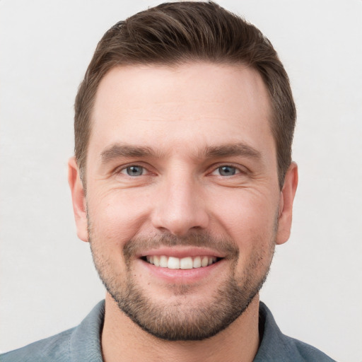 Joyful white young-adult male with short  brown hair and grey eyes