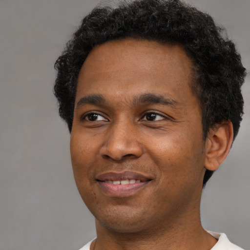 Joyful black young-adult male with short  black hair and brown eyes