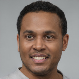 Joyful black young-adult male with short  black hair and brown eyes