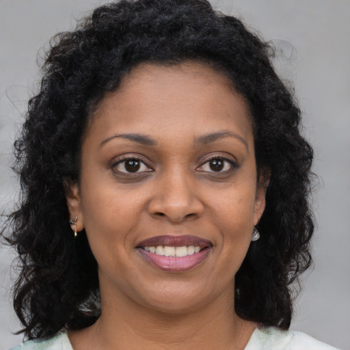 Joyful black young-adult female with long  brown hair and brown eyes