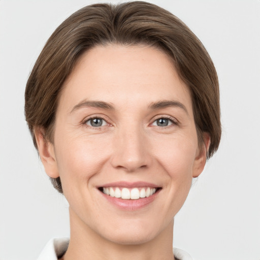 Joyful white young-adult female with short  brown hair and grey eyes