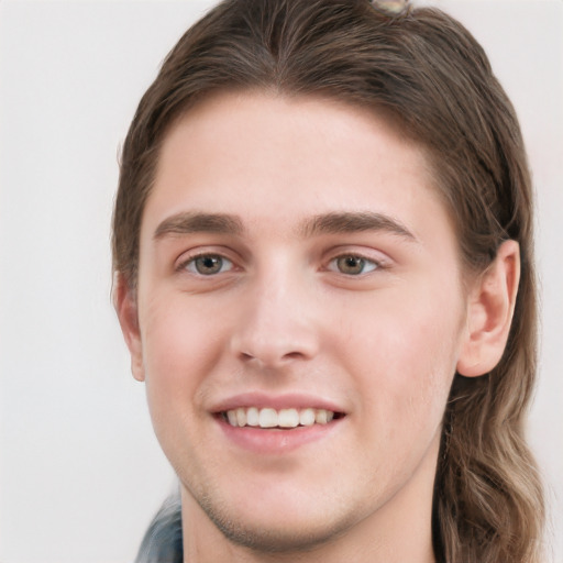 Joyful white young-adult male with long  brown hair and grey eyes