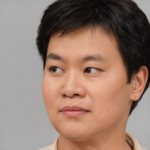 Joyful asian young-adult male with short  brown hair and brown eyes