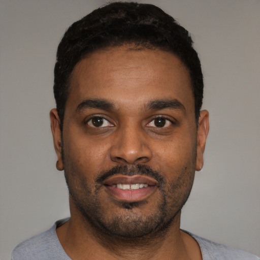 Joyful black young-adult male with short  black hair and brown eyes