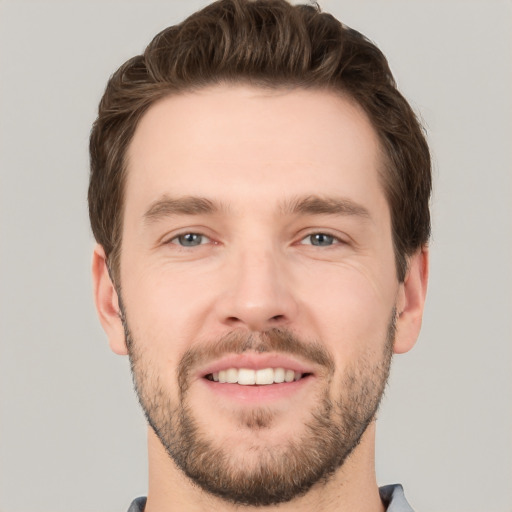 Joyful white young-adult male with short  brown hair and grey eyes