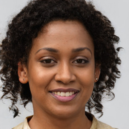 Joyful black young-adult female with long  brown hair and brown eyes