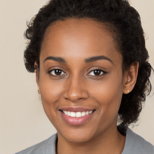 Joyful black young-adult female with long  brown hair and brown eyes