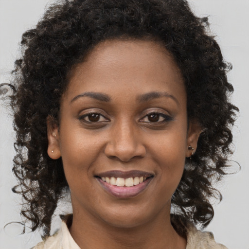 Joyful black young-adult female with long  brown hair and brown eyes