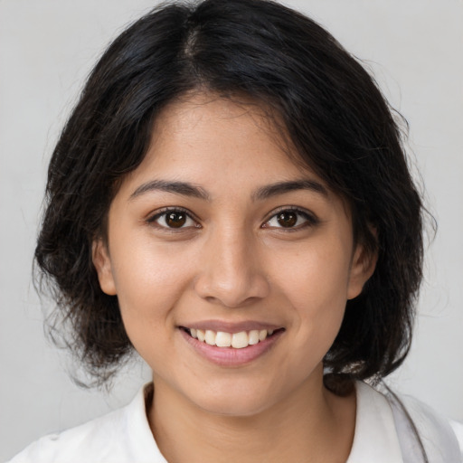 Joyful latino young-adult female with medium  brown hair and brown eyes