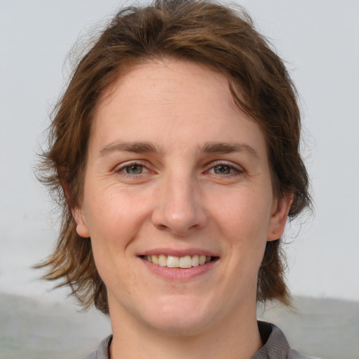 Joyful white young-adult female with medium  brown hair and grey eyes