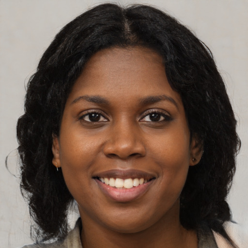 Joyful black young-adult female with long  brown hair and brown eyes