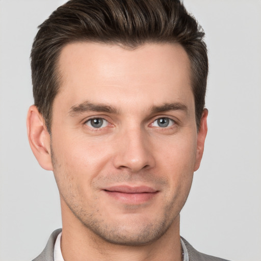 Joyful white young-adult male with short  brown hair and grey eyes