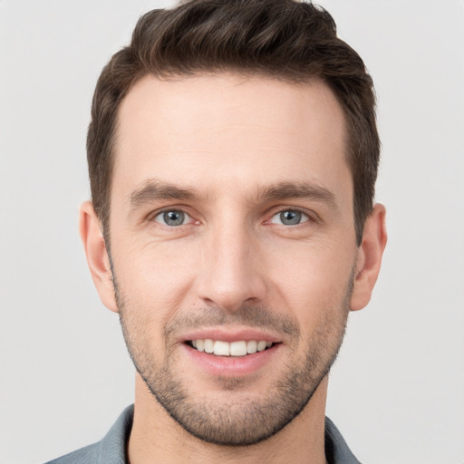 Joyful white young-adult male with short  brown hair and grey eyes