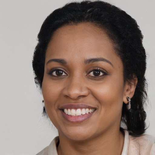Joyful black young-adult female with long  black hair and brown eyes