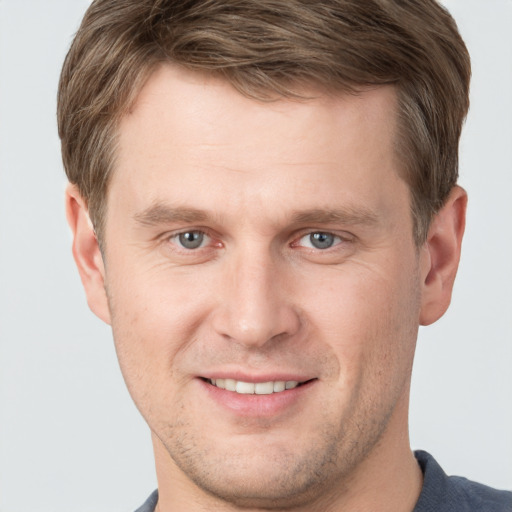 Joyful white young-adult male with short  brown hair and grey eyes