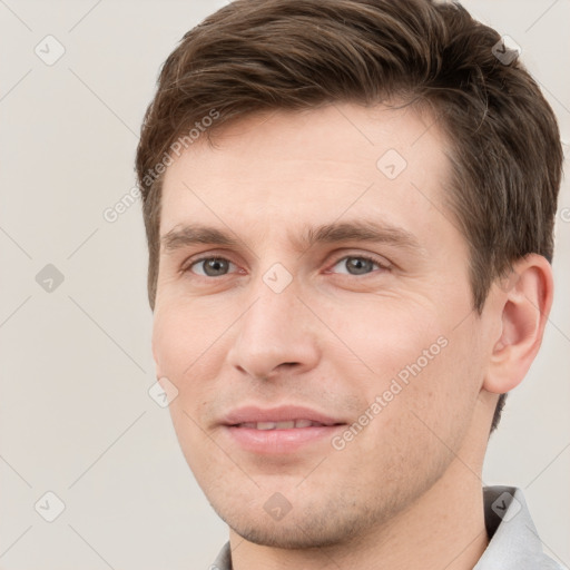 Joyful white young-adult male with short  brown hair and grey eyes