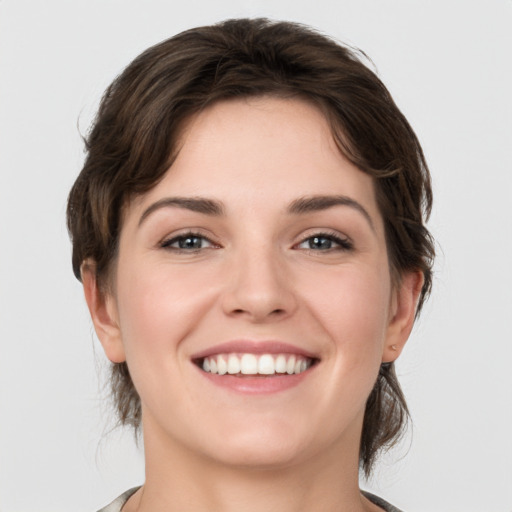 Joyful white young-adult female with medium  brown hair and grey eyes