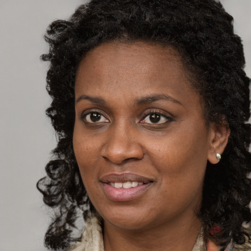 Joyful black adult female with long  brown hair and brown eyes
