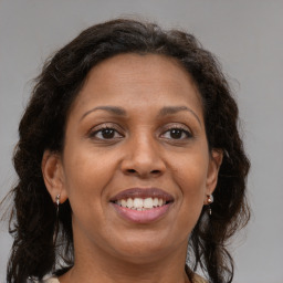 Joyful black adult female with long  brown hair and brown eyes