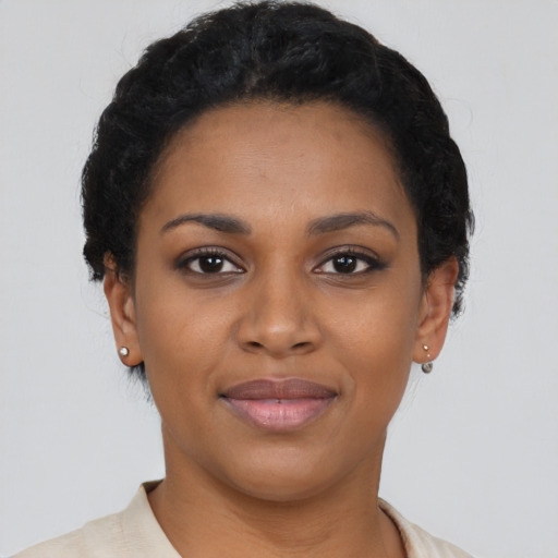 Joyful black young-adult female with short  black hair and brown eyes