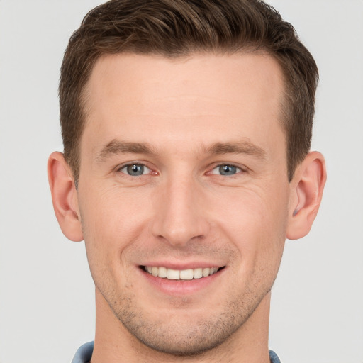 Joyful white young-adult male with short  brown hair and grey eyes