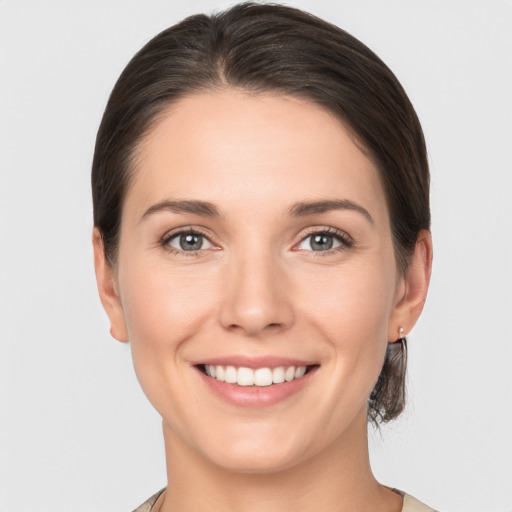 Joyful white young-adult female with medium  brown hair and grey eyes