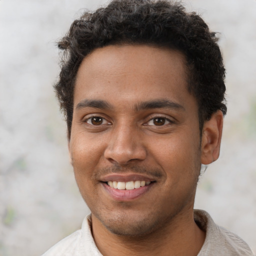 Joyful black young-adult male with short  brown hair and brown eyes