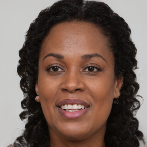 Joyful black adult female with long  brown hair and brown eyes