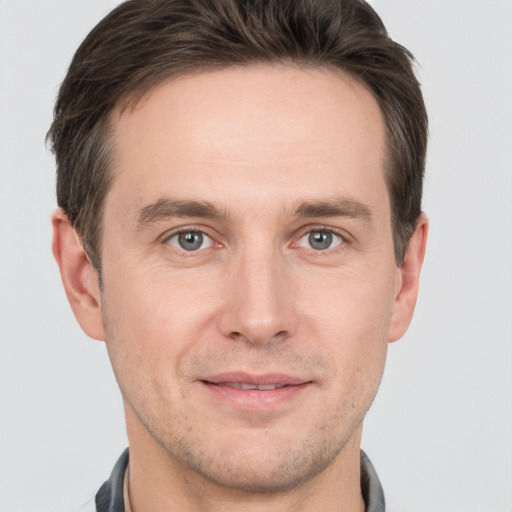 Joyful white young-adult male with short  brown hair and grey eyes