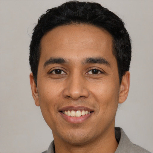 Joyful latino young-adult male with short  black hair and brown eyes