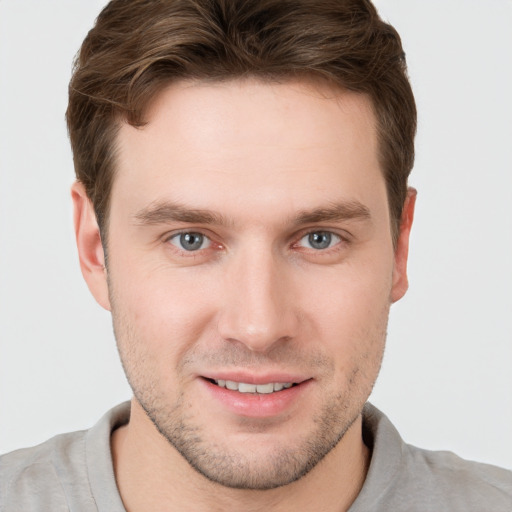 Joyful white young-adult male with short  brown hair and grey eyes