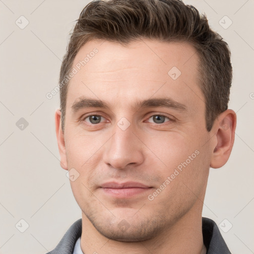 Joyful white young-adult male with short  brown hair and grey eyes