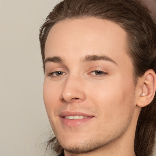 Joyful white young-adult male with long  brown hair and brown eyes