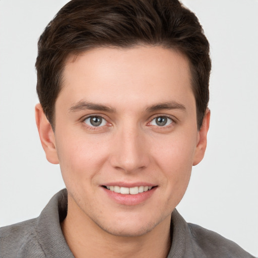 Joyful white young-adult male with short  brown hair and grey eyes