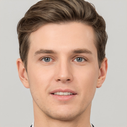 Joyful white young-adult male with short  brown hair and grey eyes