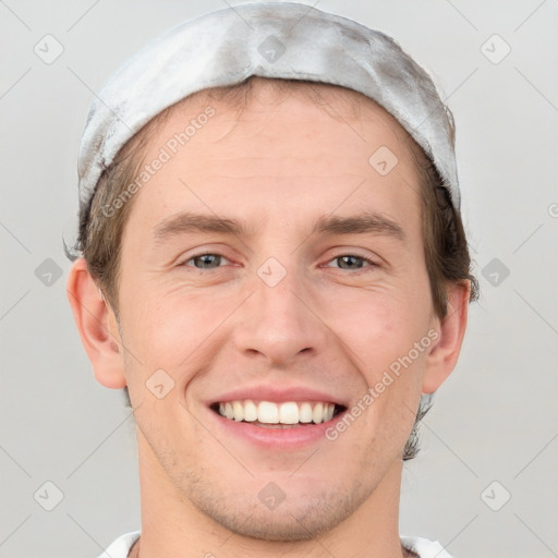 Joyful white young-adult male with short  brown hair and grey eyes