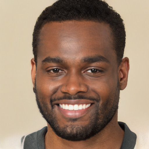 Joyful black young-adult male with short  brown hair and brown eyes