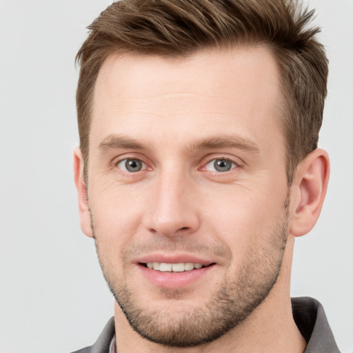 Joyful white young-adult male with short  brown hair and grey eyes