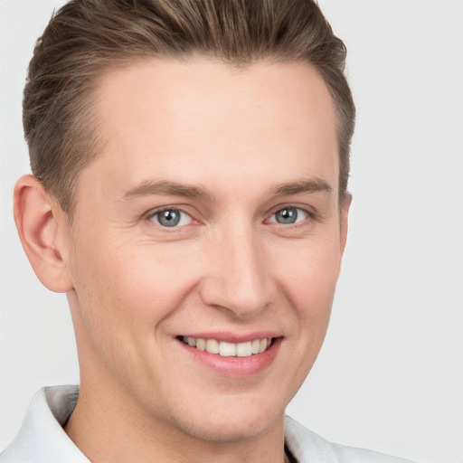 Joyful white young-adult male with short  brown hair and grey eyes