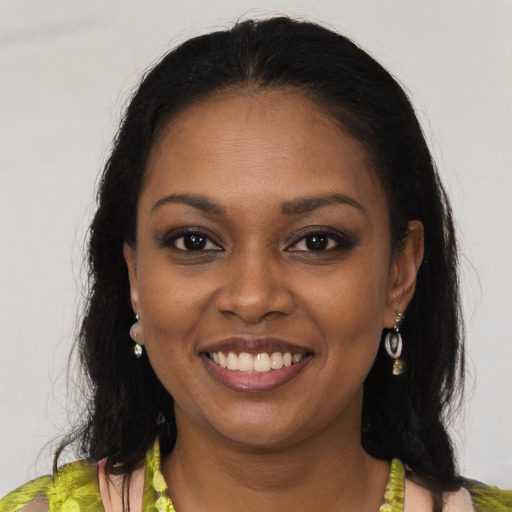 Joyful black young-adult female with long  brown hair and brown eyes