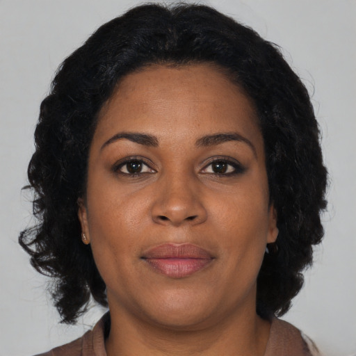 Joyful black adult female with long  brown hair and brown eyes
