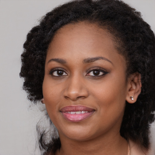Joyful black young-adult female with long  black hair and brown eyes