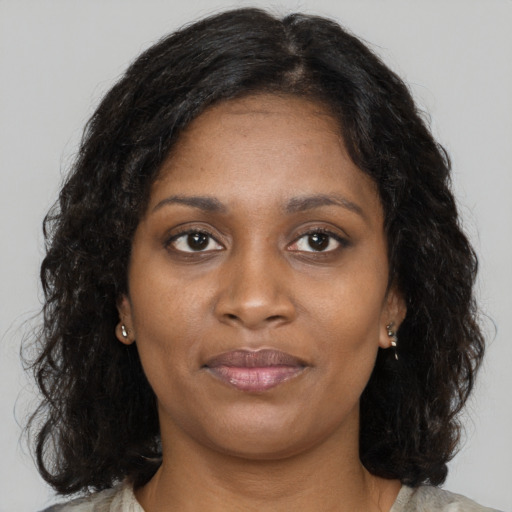 Joyful black young-adult female with long  brown hair and brown eyes
