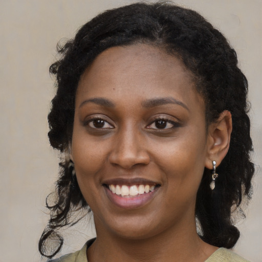 Joyful black young-adult female with long  black hair and brown eyes