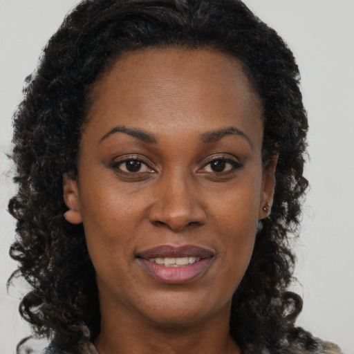 Joyful black adult female with long  brown hair and brown eyes